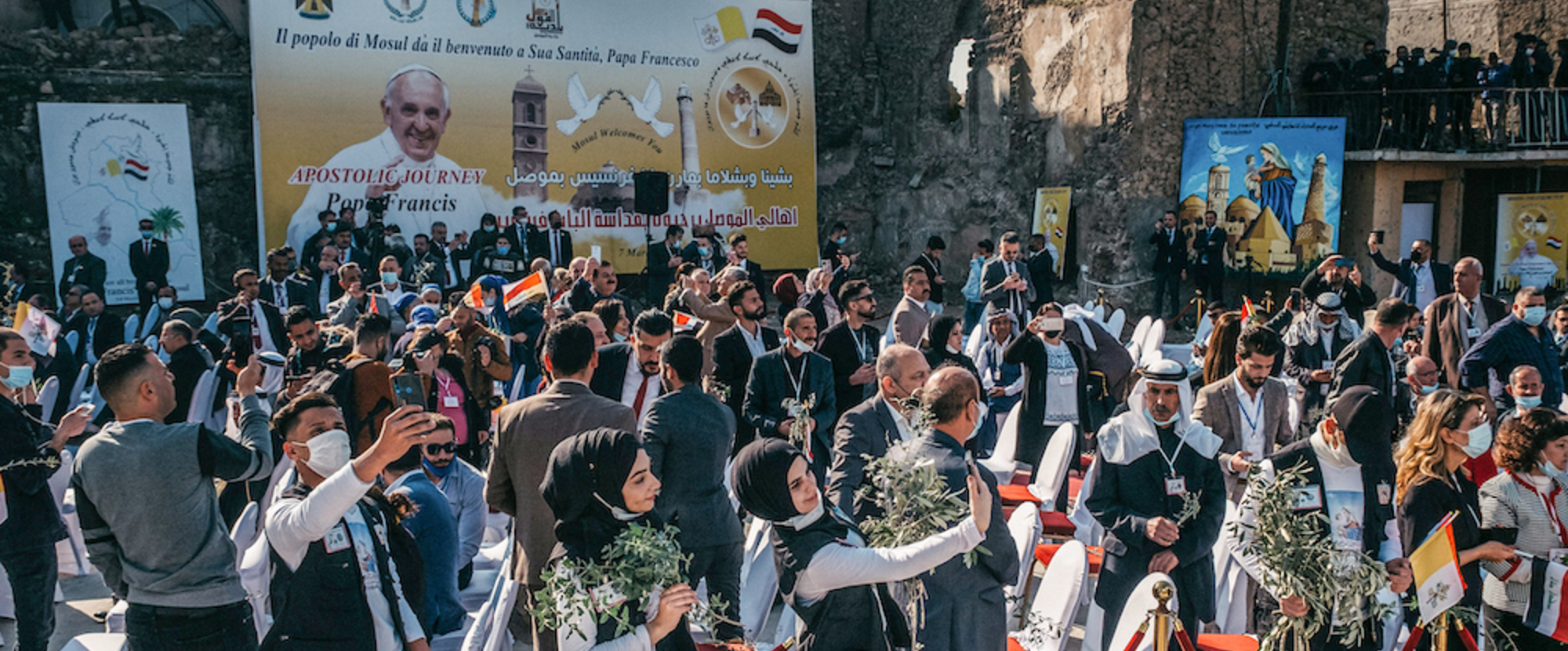 Viele Menschen, darunter junge muslimische Frauen mit Olivenzweigen, warten am Straßenrand auf die Ankunft von Papst Franziskus am 7. März 2021 in Mossul.