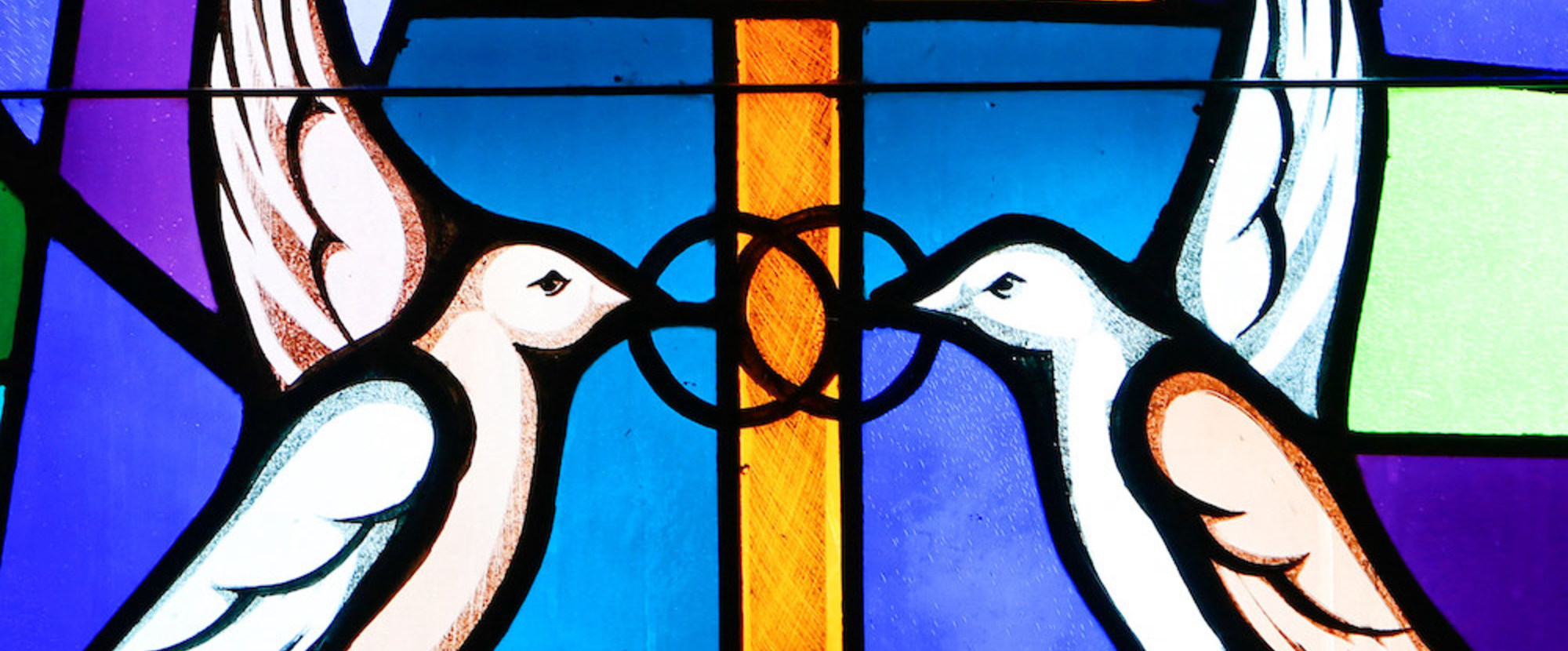 Buntglasfenster mit einer Darstellung von zwei weißen Tauben am 7. Mai 2017. Sie halten zwei ineinander verschlungene Ringe in den Schnäbeln, ein Symbol für Ehe. (Aufnahmeort unbekannt)