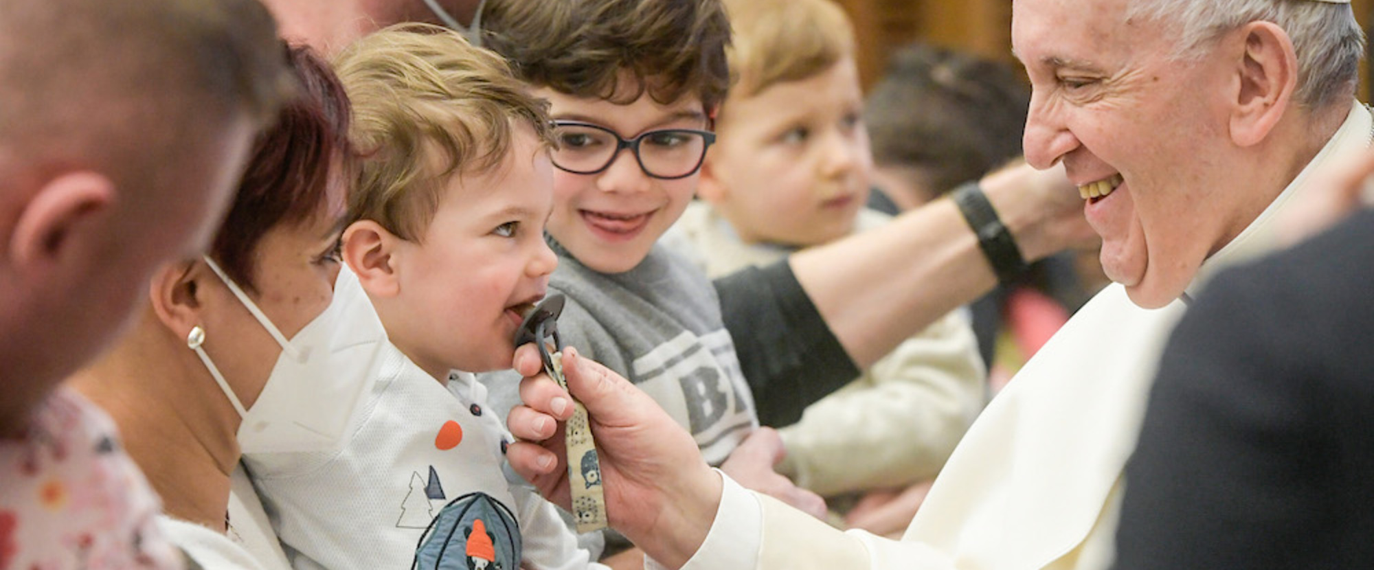 Papst Franziskus zieht an dem Schnuller eines kleinen Kindes bei der Generalaudienz am 16. Februar 2022 im Vatikan.