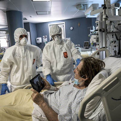 Ärzte und Pfleger in Schutzkleidung stehen am 29. April 2020 neben einem im Bett liegenden Covid-19-Patienten auf der Intensivstation des Krankenhauses San Filippo Neri in Rom. Der Mann hält ein Tablet zum Skypen.