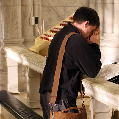 Ein junger Mann betet in einer Kniebank während einer Vigil in der Saint Patrick's Cathedral in New York am 7. Dezember 2016. Er kniet und hat die Hände zum Gebet gefaltet.