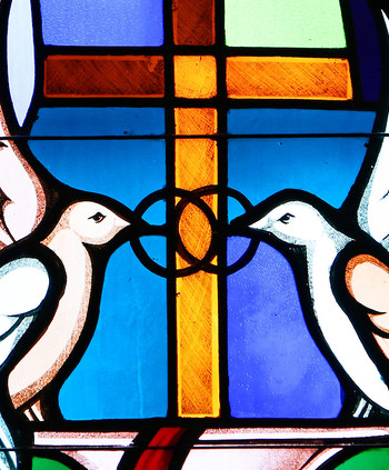 Buntglasfenster mit einer Darstellung von zwei weißen Tauben am 7. Mai 2017. Sie halten zwei ineinander verschlungene Ringe in den Schnäbeln, ein Symbol für Ehe. (Aufnahmeort unbekannt)