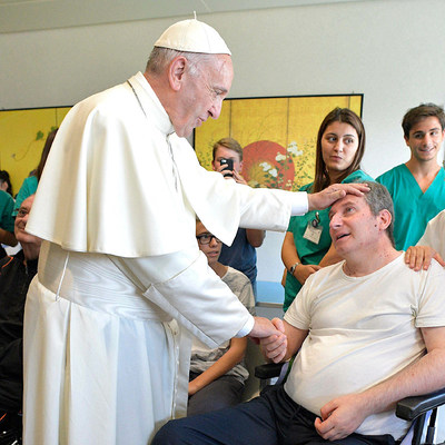 Papst Franziskus hält die Hand und legt eine Hand auf die Stirn eines Mannes im Rollstuhl am 22. September 2017 im Rehabilitationszentrum der Stiftung Santa Lucia in Rom. Der Papst besucht einmal im Monat an einem 'Freitag der Barmherzigkeit' Einrich