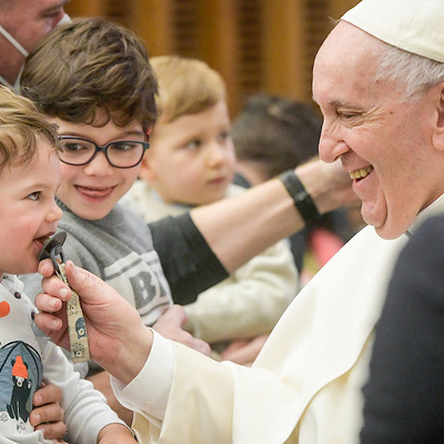 Papst Franziskus zieht an dem Schnuller eines kleinen Kindes bei der Generalaudienz am 16. Februar 2022 im Vatikan.