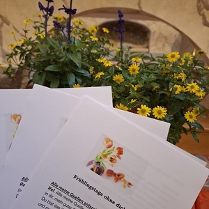 Liedhefte des Gottesdienstes vor blühenden Blumen