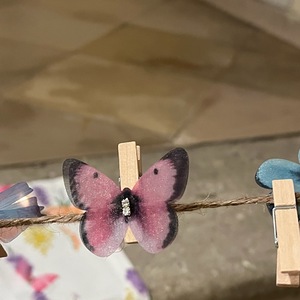 Schmetterling, der mit Klammer befestigt an Schnur hängt